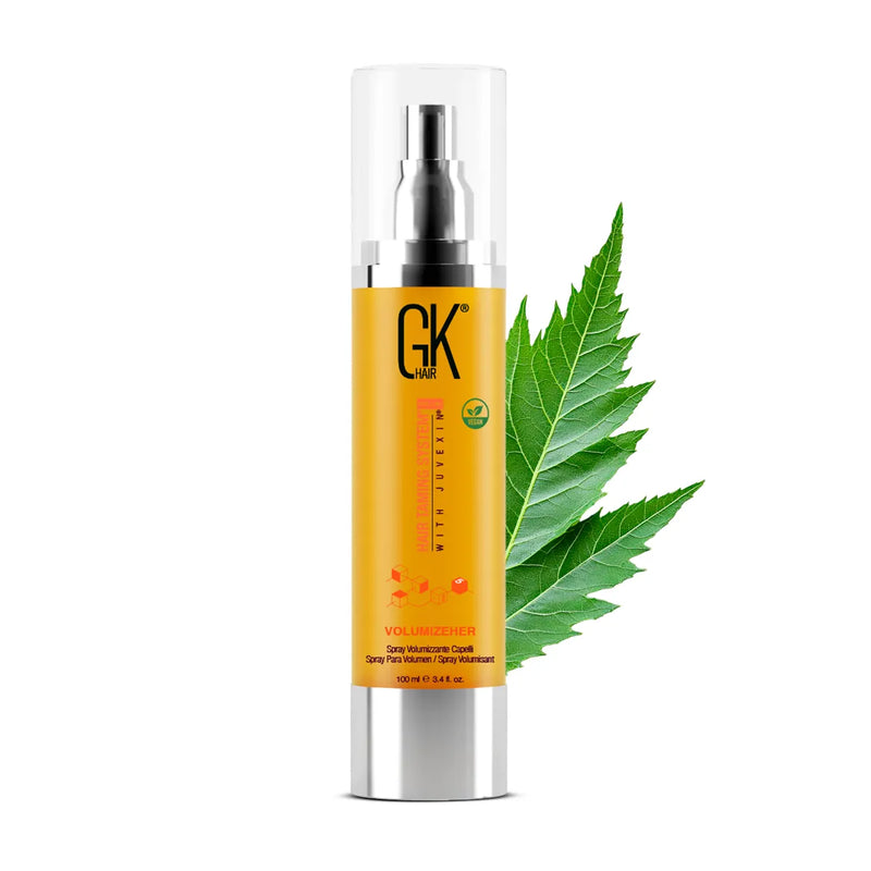 GK Hair VolumizeHer Spray Pro 100 ml golden bottle with a clear overcap, standing beside a green leaf on white