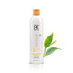 GK Hair Anti-Dandruff Shampoo 250 ml white bottle with an orange cap, front view beside fresh green tea leaves